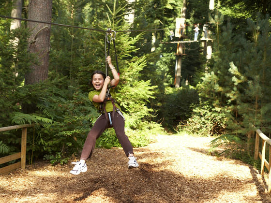 Young girl coming along a zip wire smiling