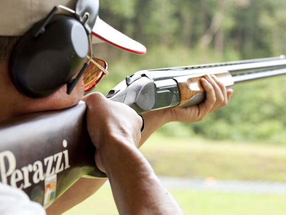Gentleman with perazzi gun and ear defenders clay shooting