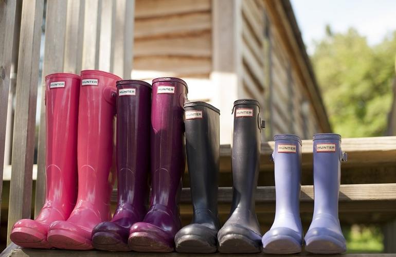 Selection of bight coloured wellies shown on the steps of a lodge