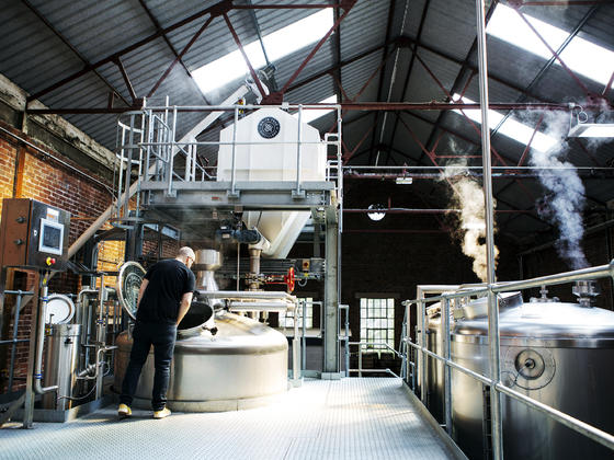 Distillery work in progress, large stainless steel vats with steam rising